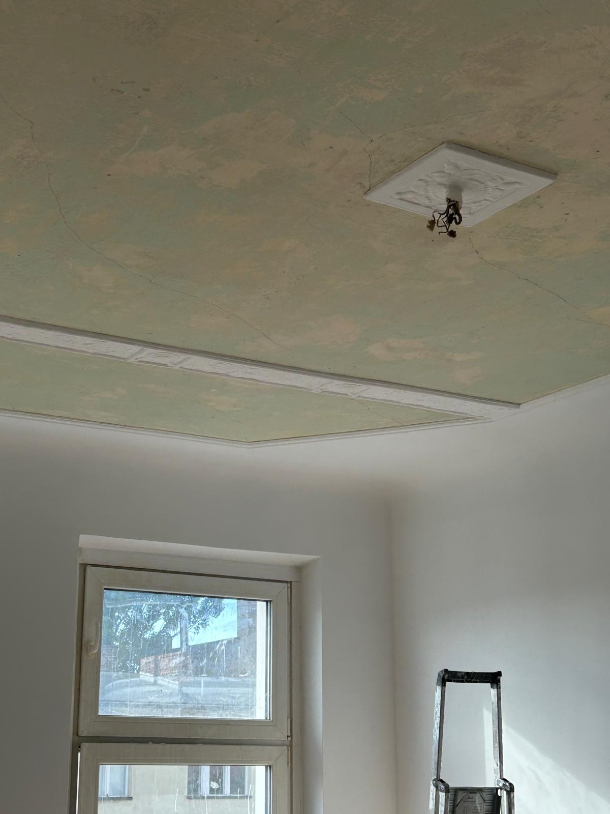 Decke mit aufgearbeiteter Stuckrosette und sichtbaren Feinheiten der alten Bausubstanz